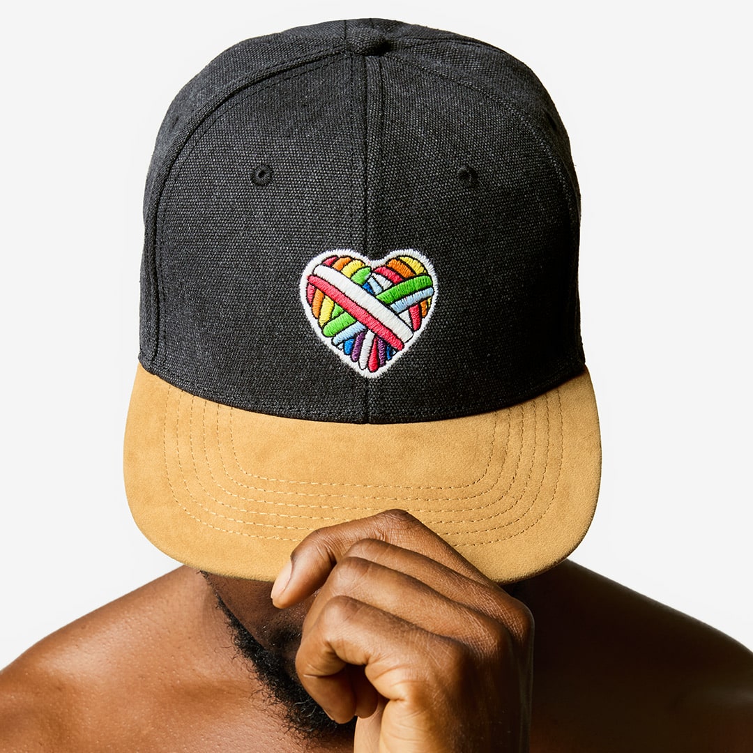 "Woolen Heart" Skater-Cap with a heart motif made of gay sheep wool on a male model’s head.