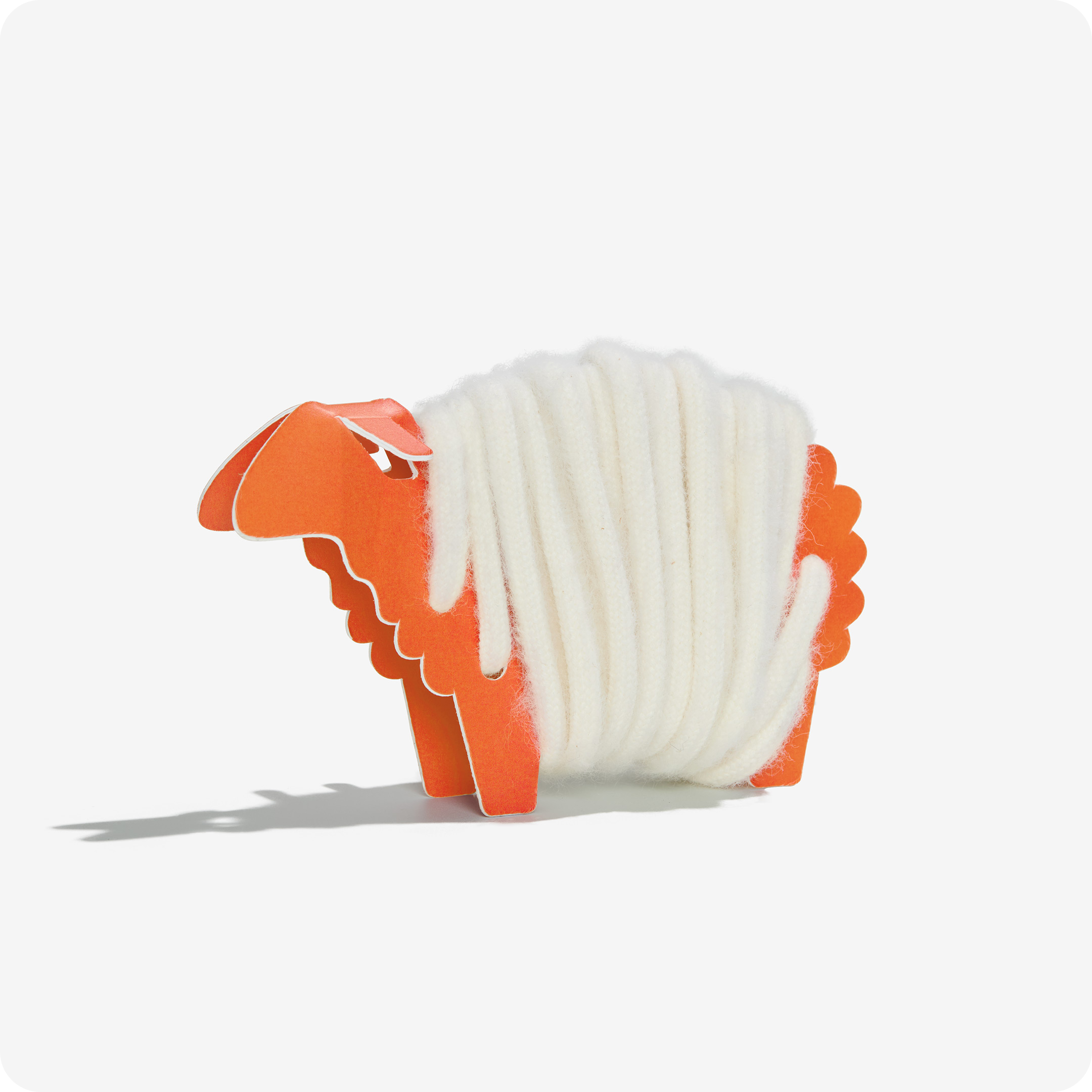 Rainbow Wool Laces made of gay sheep wool wrapped around an orange paper sheep in front of a white background.