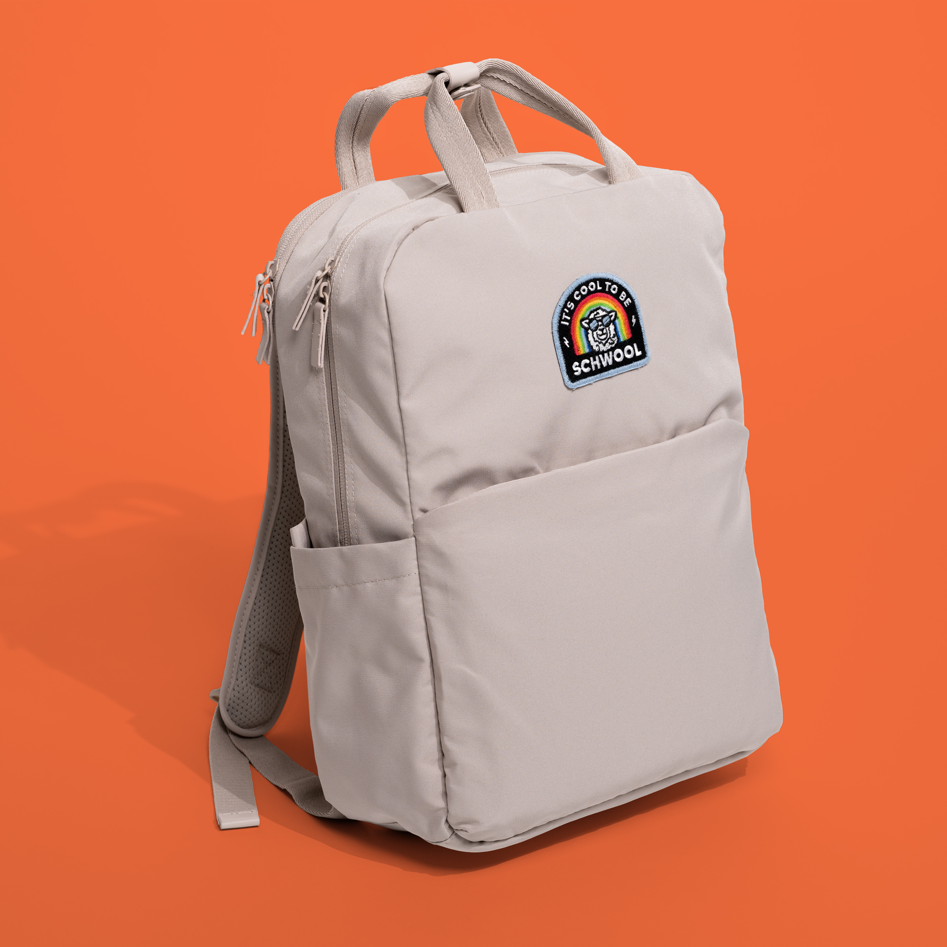 Quarter view of the limited edition backpack "It's cool to be schwool" on an orange background 