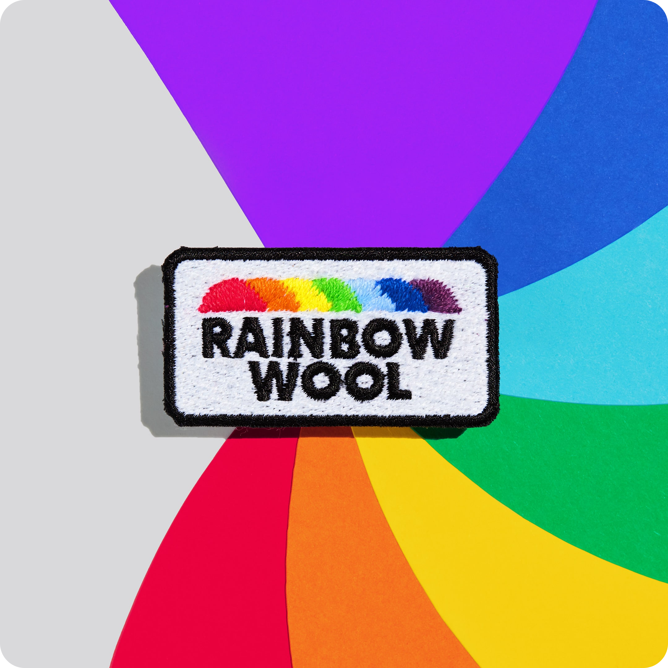 Patch "Rainbow Wool" aus schwuler Schafwolle auf einem bunten Hintergrund.