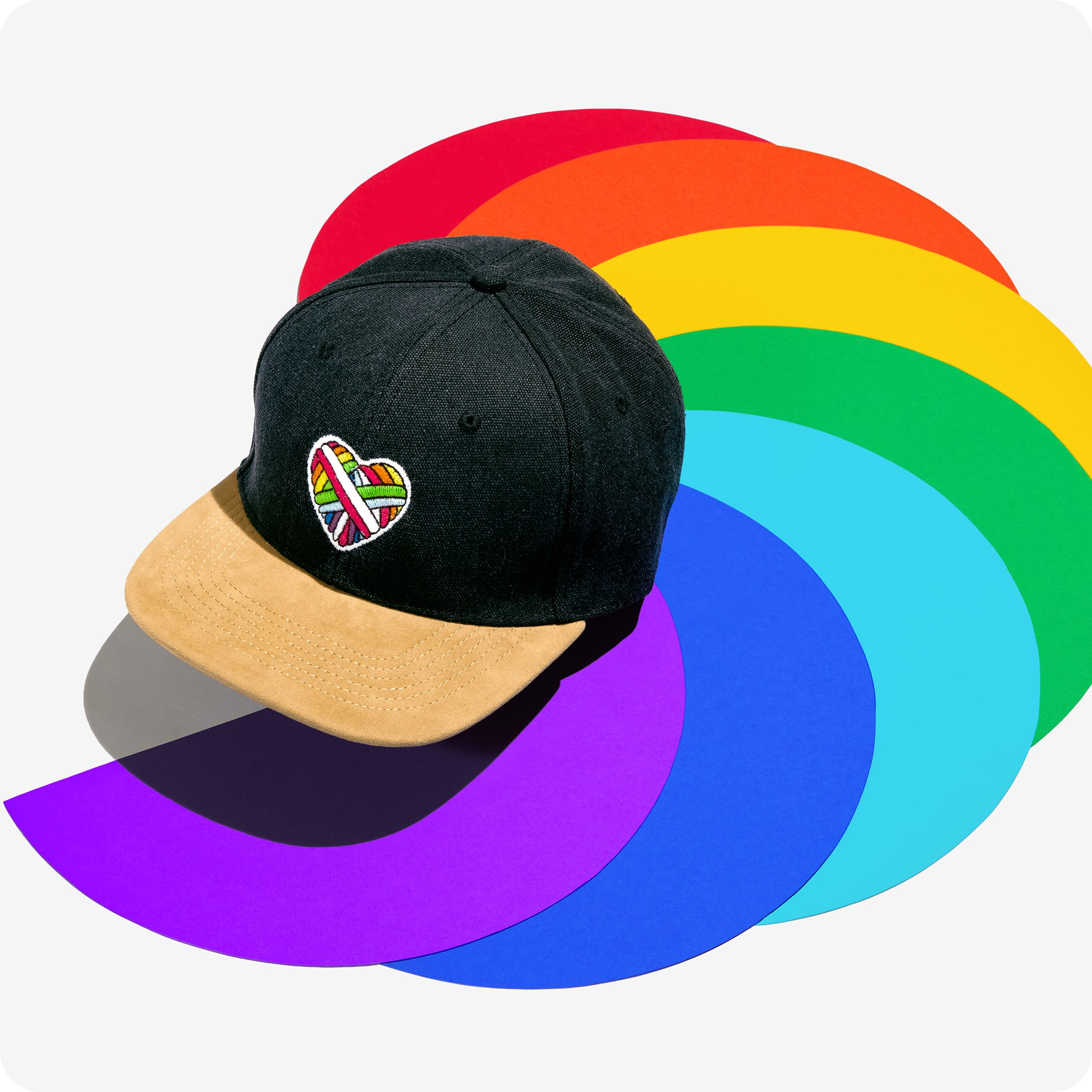 "Woolen Heart" Skater-Cap mit einem Herz-Motiv aus schwuler Schafwolle auf einem bunten Hintergrund.