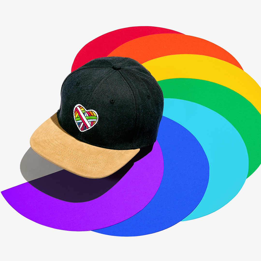 "Woolen Heart" Skater-Cap mit einem Herz-Motiv aus schwuler Schafwolle auf einem bunten Hintergrund.