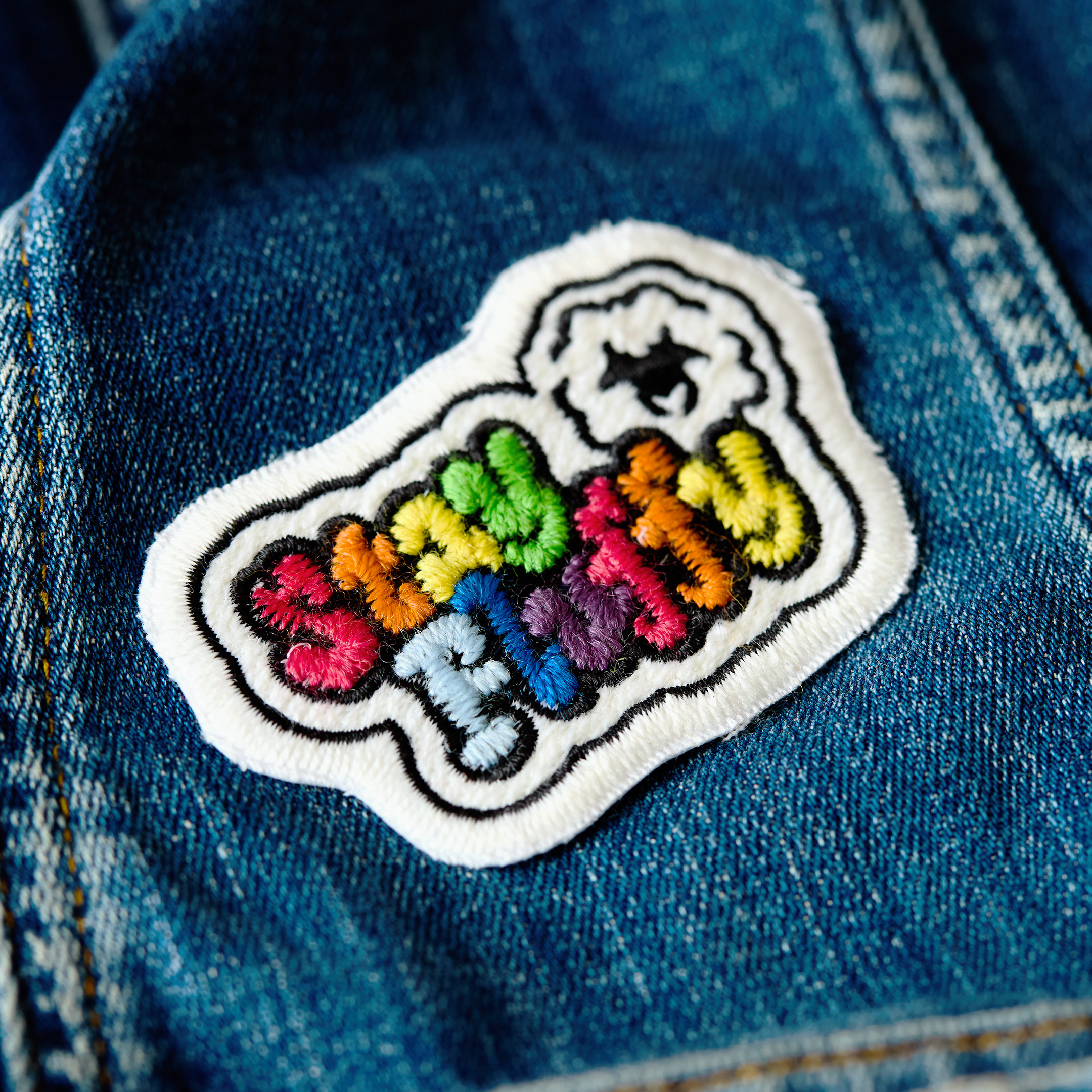 Patch "stay fluffy" made of gay sheep wool on denim.