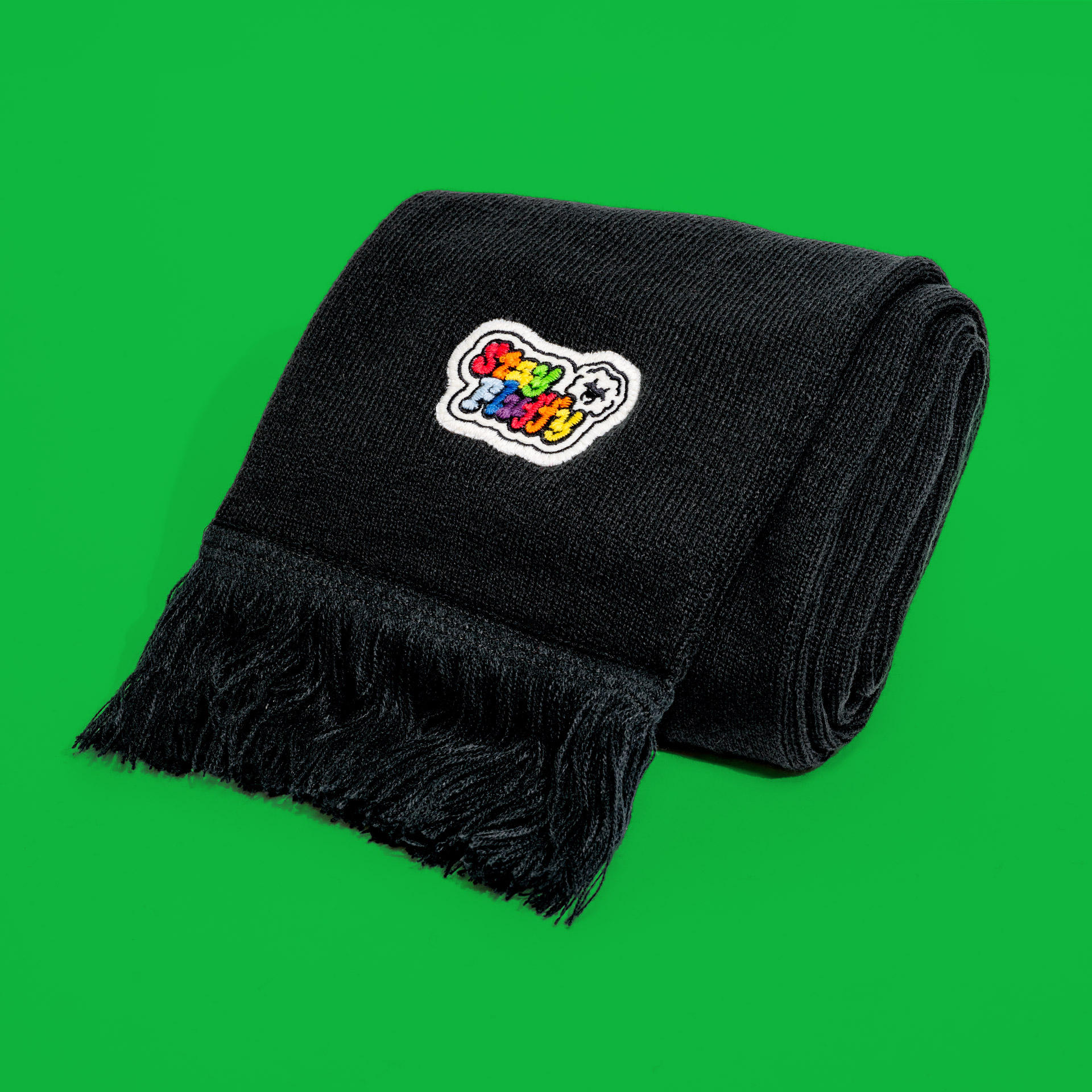 Full view of the rolled limited edition scarf "stay fluffy" on a green background