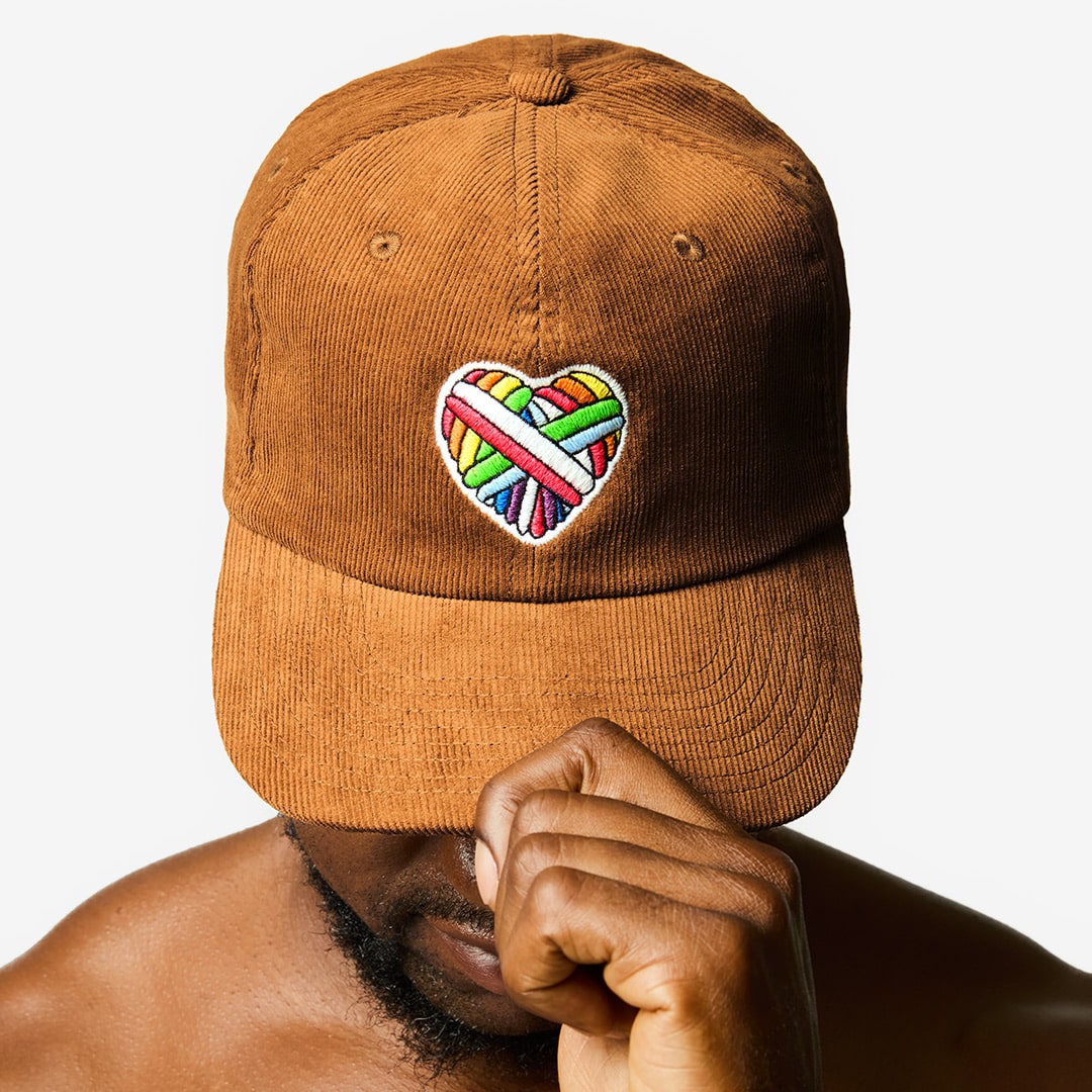 "Woolen Heart" Corduroy Cap with a heart motif made of gay sheep wool on a male model’s head.